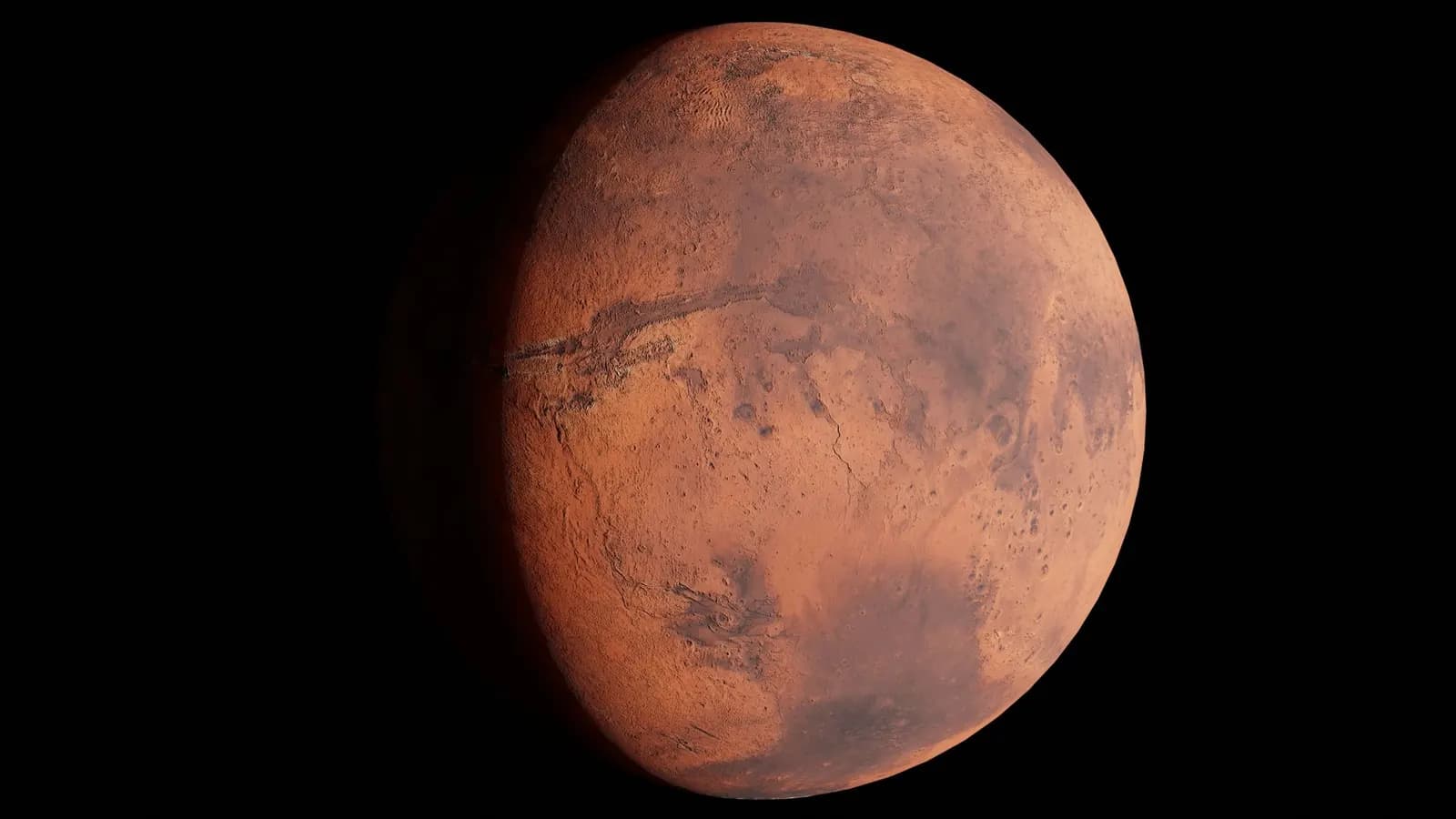 The red planet Mars, its rust-coloured surface lit on one side against black space