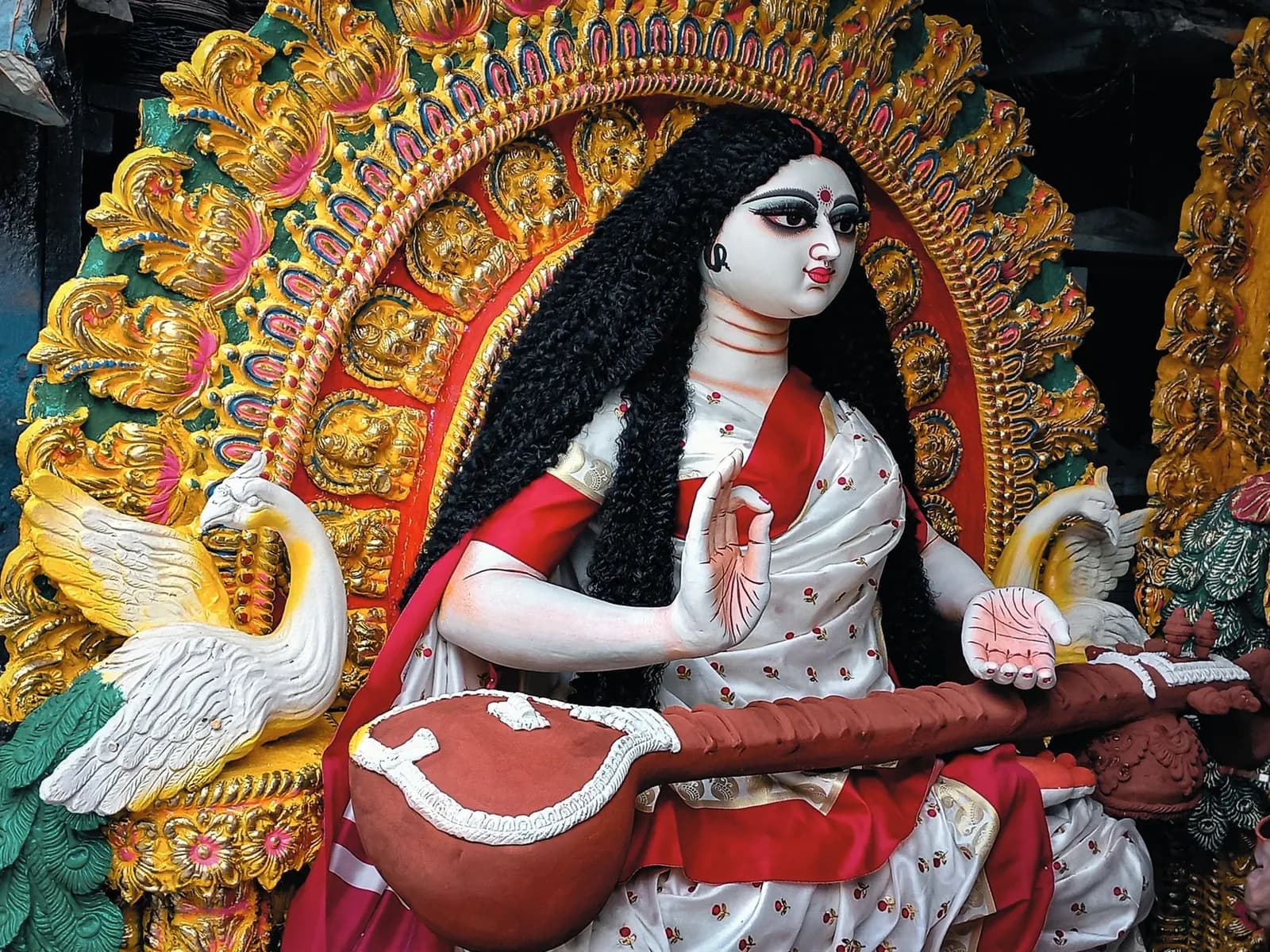 Painted clay idol of Saraswati holding a veena, with a white swan beside her, in Kolkata