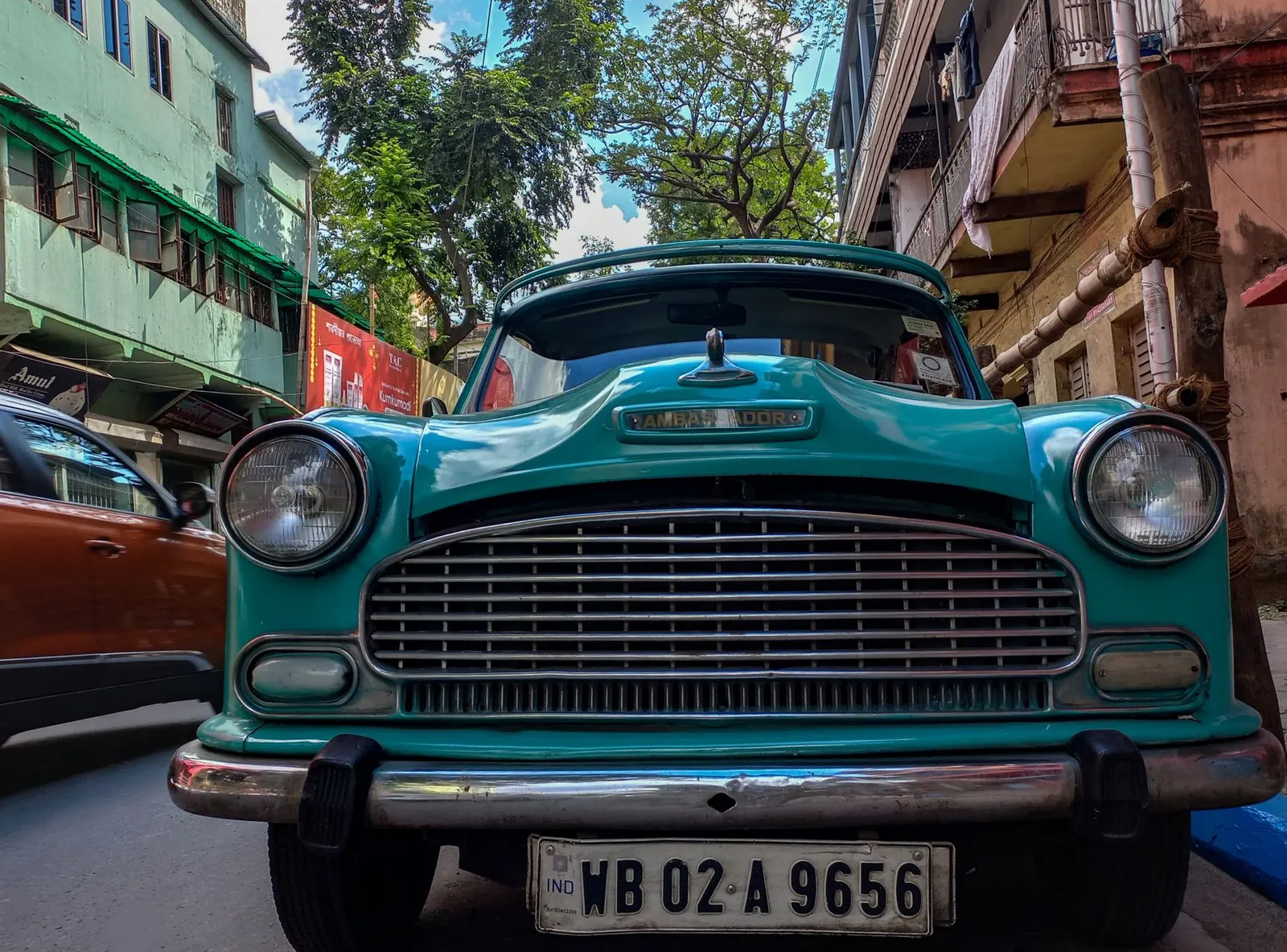Front of a teal Ambassador car on a Kolkata street, its white number plate reading WB 02 A 9656