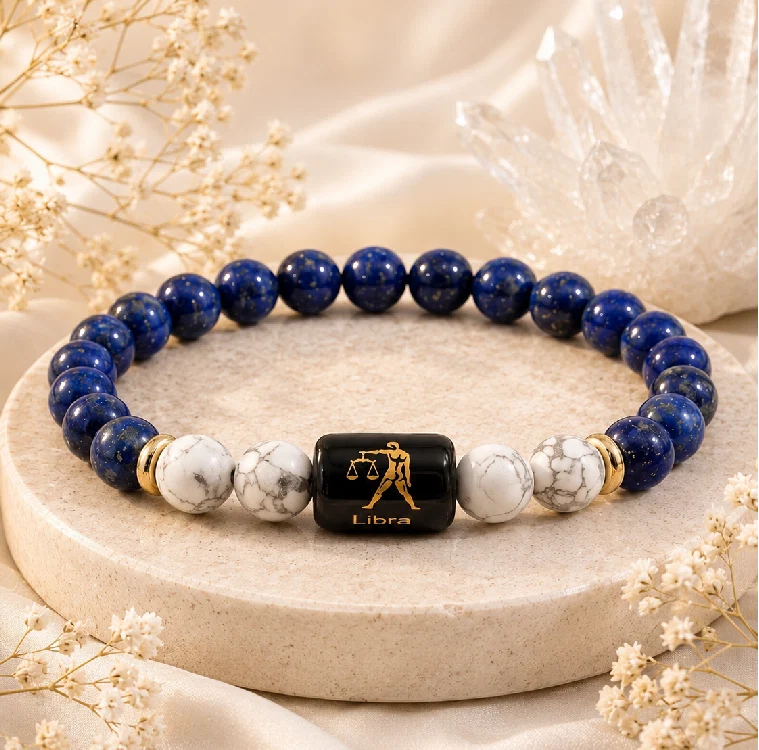 Deep blue lapis lazuli and orange carnelian beads beside small white flowers on a marble surface