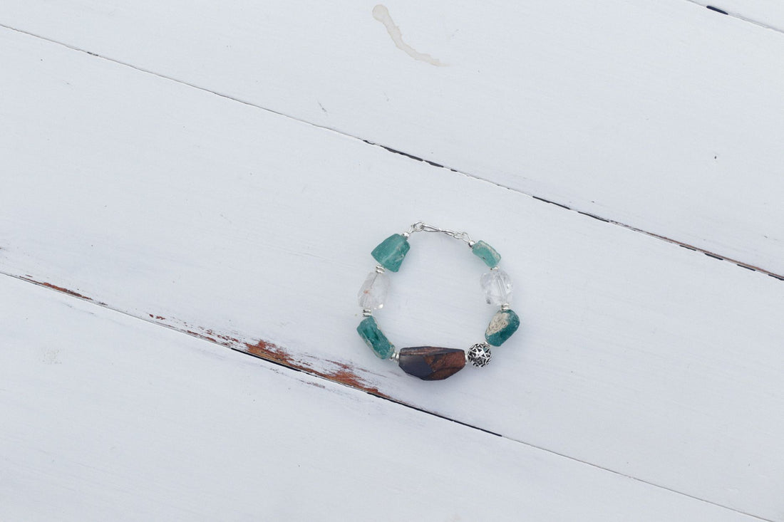 Green aventurine beads strung with clear quartz on a plain wooden surface