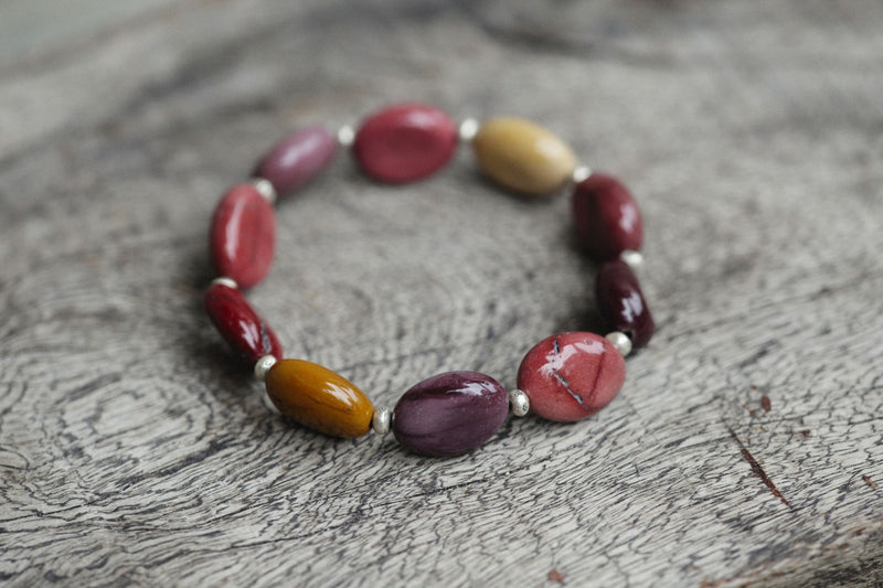 Close-up of a natural stone bead bracelet coiled on a wooden surface
