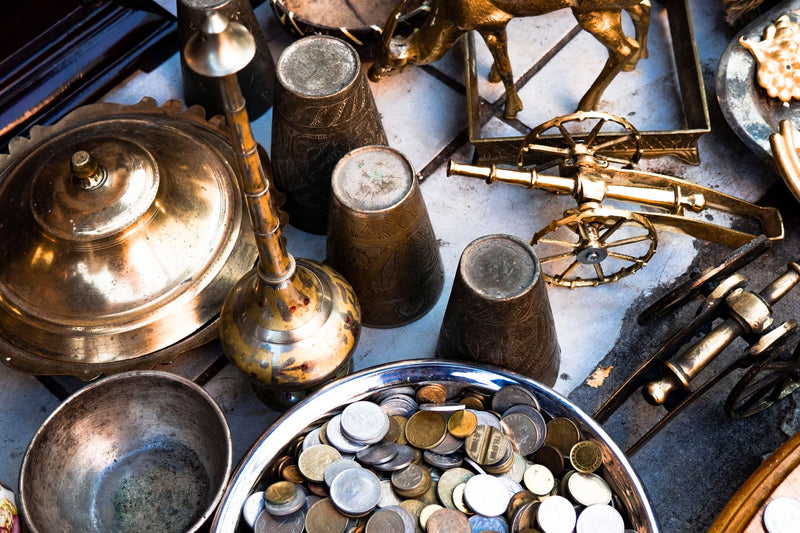 Old brass coins spilling from a small clay pot onto rough jute cloth