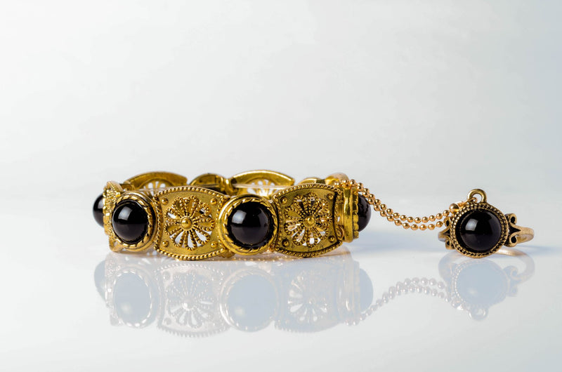Polished black onyx beads with clear quartz on a dark slate surface