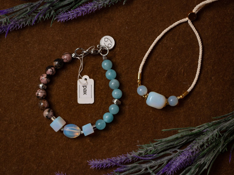 Two natural gemstone bead bracelets lying side by side on a linen surface