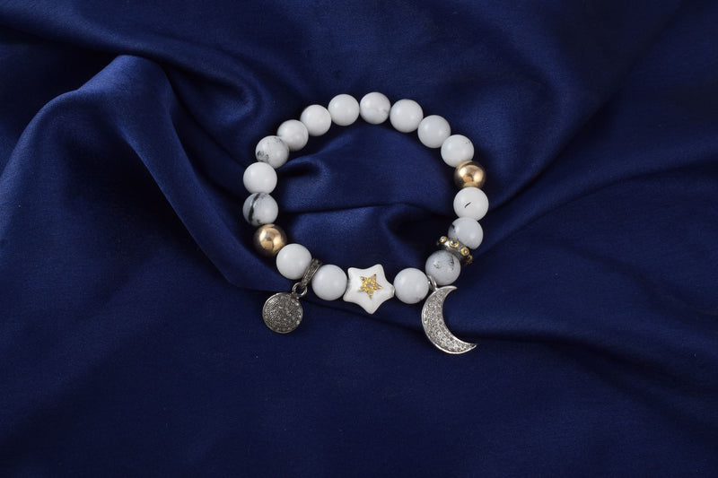 White howlite and deep blue lapis lazuli beads resting on grey linen in soft light