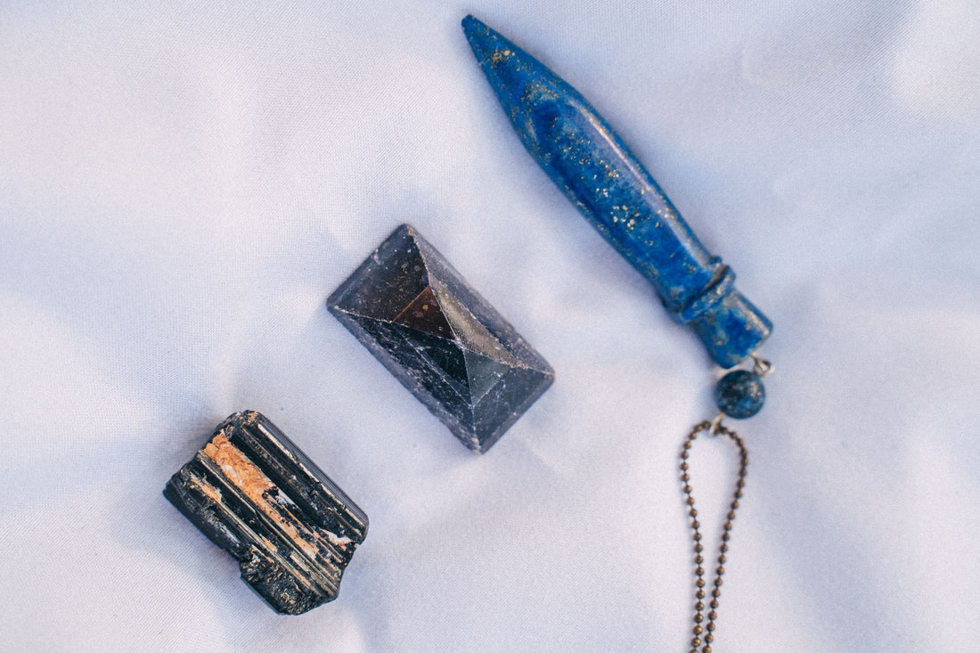 Deep blue lapis lazuli beads strung beside white howlite beads on a pale marble surface
