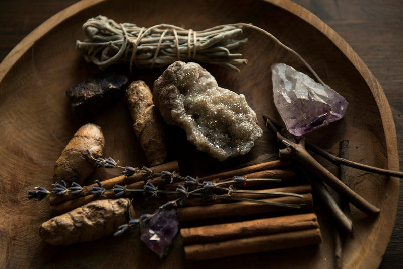 A raw purple amethyst cluster beside polished black onyx stones on dark wood