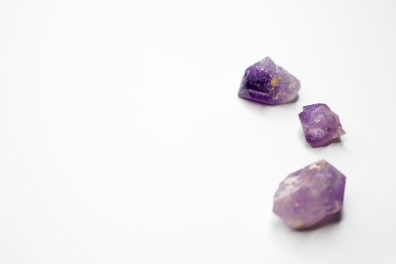 Deep purple amethyst points beside blue lapis lazuli stones on a dark surface