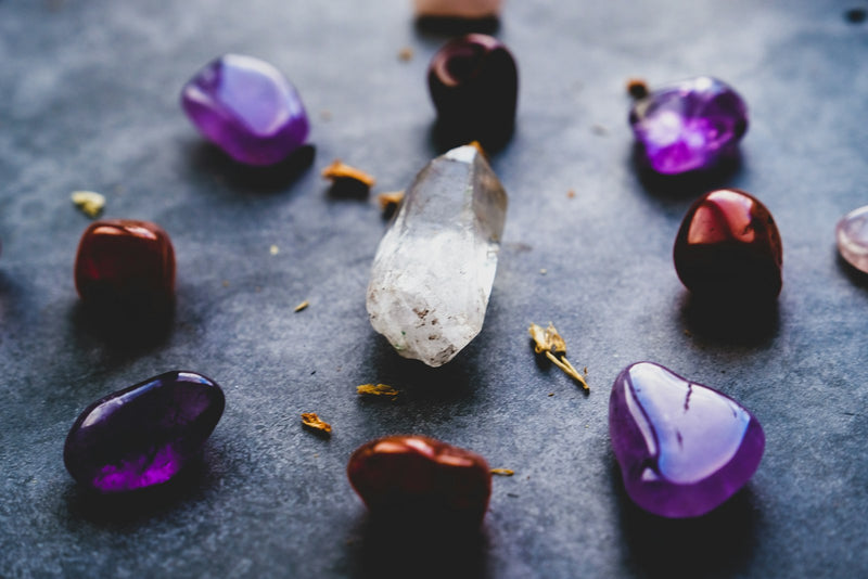An assortment of polished coloured gemstones on a dark slate surface
