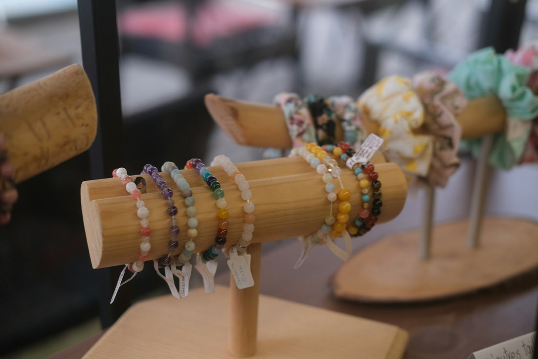 A row of assorted crystal bead bracelets in different colours laid on kraft paper beside a ribbon