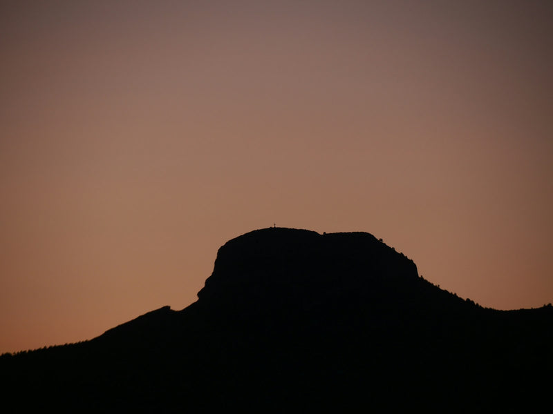 The sun rising over a horizon of silhouetted hills
