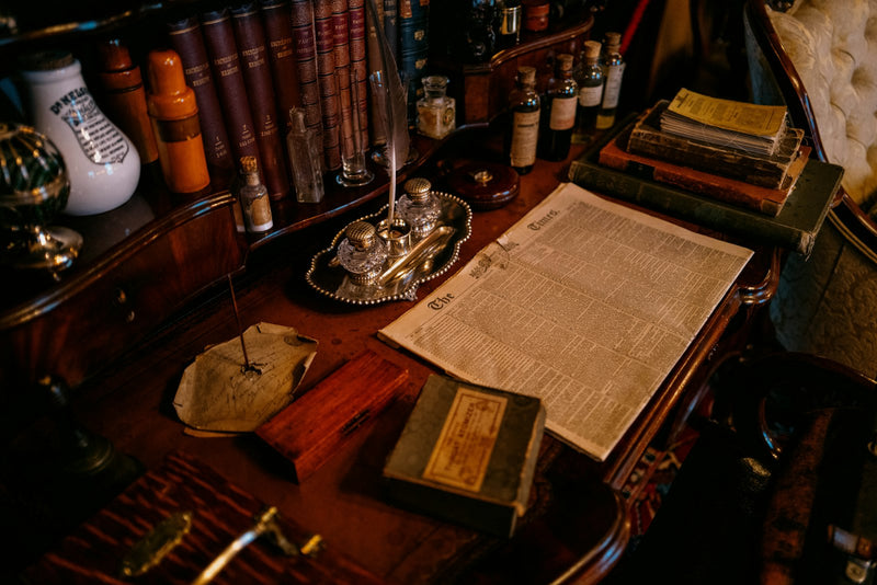 An old paper calendar beside a pocket watch on a wooden desk