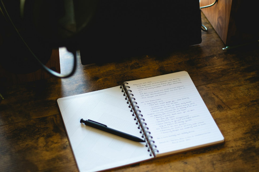 An open notebook and pen on a wooden desk in morning light